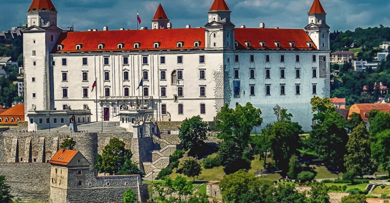 Widok na Zamek w Bratysławie. Wokół wiele drzew.