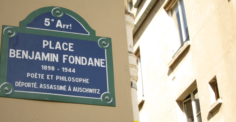 Zdjęcie przedstawiające fragment paryskiej ulicy - Place Benjamin Fondane. Na fasadzie kamienicy zawieszona jest niebieska tabliczka z nazwą placu, z datą i miejscem śmierci Benjamina Fondaine.
